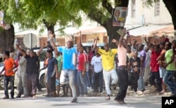In this photo taken Monday, Oct. 26th, 2015 and made available Wednesday, Oct. 28th, 2015, youths supporting the opposition party dance and chant, predicting a win for their candidate, outside the Electoral Commission office in Stone Town, Zanzibar, a sem