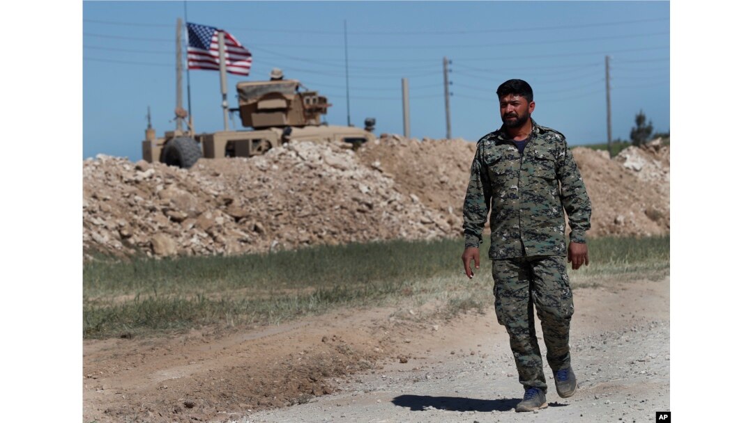 FILE - A U.S-backed YPG soldier passes a U.S. position near Manbij, Syria, April 4, 2018.