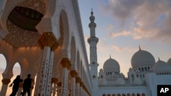 Turis berjalan di Masjid Agung Sheikh Zayed saat senja di Abu Dhabi, Uni Emirat Arab, Rabu, 9 Desember 2020. (AP Photo/Jon Gambrell)