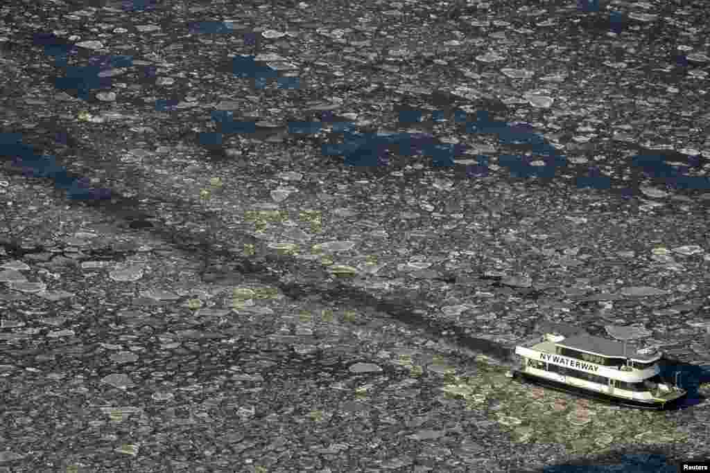 A commuter ferry navigates through the ice flow in the Hudson River between New Jersey and lower Manhattan in New York.