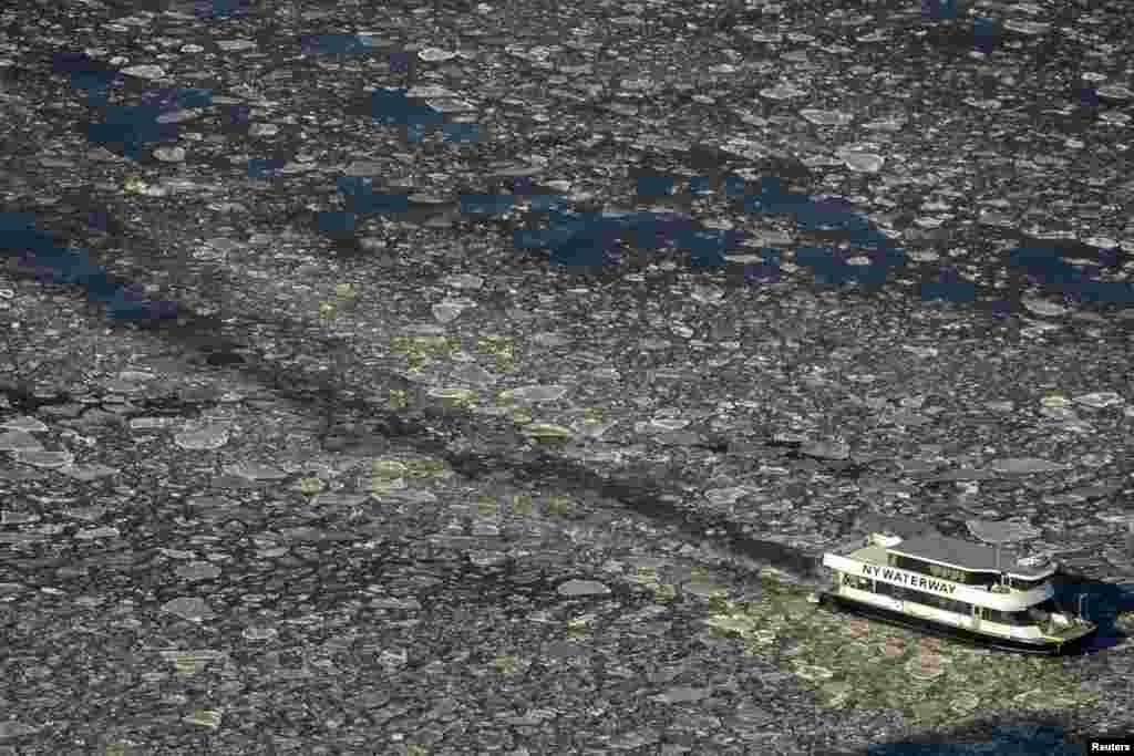 A commuter ferry navigates through the ice flow in the Hudson River between New Jersey and lower Manhattan in New York. 