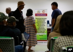 FILE - Patients wait near a banner informing of a delay in service due to a cyberattack at the Dharmais Cancer Hospital in Jakarta, Indonesia, May 15, 2017.