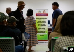 Para pasien menunggu dekat papan pengumuman yang memberitahukan penundaan layanan karena serangan siber di RS Kanker Dharmais di Jakarta, Indonesia, 15 Mei 2017.