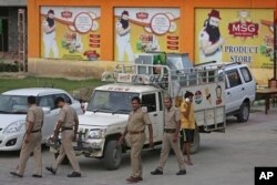 FILE - Indian policemen walk in front of a store belonging to Dera Sacha Sauda sect chief Gurmeet Ram Rahim Singh after it was sealed by authorities, near Sonipat, India, Aug. 26, 2017.