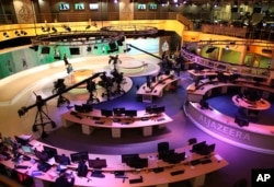 FILE - Staff members of Al-Jazeera International work at the news studio in Doha, Qatar, Jan. 1, 2015.