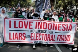 Pendukung calon presiden Prabowo Subianto membawa spanduk dalam unjuk rasa dekat gedung Mahkamah Konstitusi menjelang sidang putusan pilpres 2019, 27 Juni 2019. (Foto: AP)