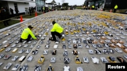 FILE - Colombian anti-narcotics policemen inspect packs of cocaine, seized from the Los Usuga criminal gang, at the police base in Necocli, Feb. 24, 2015. 