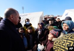 Presiden Turki Recep Tayyip Erdogan (kiri) berbicara dengan para penyintas gempa saat mengunjungi pusat kota yang hancur akibat gempa di Kahramanmaras, Turki selatan, Rabu, 8 Februari 2023.