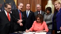 낸시 펠로시 하원 의장이 15일 의회에서 상원에 제출하는 탄핵소추안에 서명을 하고 있다. 