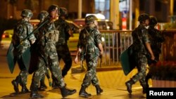 An armed paramilitary policeman gestures as he patrols with other policemen along a street in Kashgar, Xinjiang Uighur Autonomous Region, China, June 30, 2013.