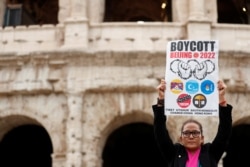 FILE - A demonstrator holds a placard as activists demonstrate outside the Colosseum, calling on G-20 leaders to boycott the Beijing 2022 Winter Olympics due to China's treatment of Tibet, Uyghur Muslims and Hong Kong, in Rome, Italy, Oct. 29, 2021.