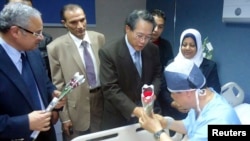 Egyptian Tourism Minister Hisham Zaazou (L) and South Korea's Consul to Egypt Lim Wan Shun (C) hand flowers to a South Korean tourist who was injured in a blast on a bus in Taba, at a hospital in Sharm El-Sheik hospital, southern Sinai, Feb. 17, 2014.