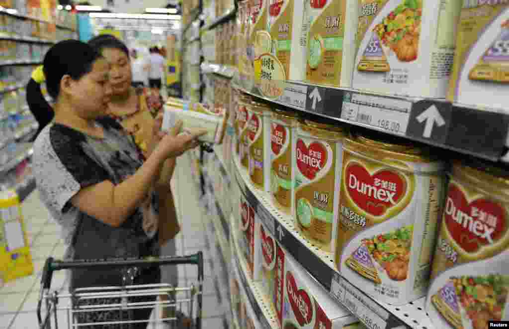 A sales assistant (back) helps a customer to select Dumex milk powder at a supermarket in Hefei, Anhui province. New Zealand's Fonterra apologized for a milk powder contamination scare in China that has raised safety concerns.
