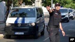 Policajac usmerava kolonu koja prevozi optužene za pokušaj puča u Crnoj Gori, Podgorica, 20. jul 2017. godine (Foto: AP/Risto Božović)