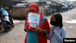 Seorang ibu dan anaknya mengenakan masker wajah untuk melindungi dari penularan virus corona (Covid-19) di Depok, 13 April 2020. (Foto: Reuters)