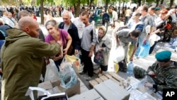 FILE - Volunteers share food and water for residents in the town of Luhansk, eastern Ukraine, Sept. 14, 2014