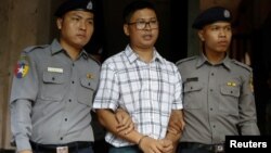 Detained Reuters journalist Wa Lone is escorted by police officers at Insein court in Yangon, Myanmar, July 16, 2018. 