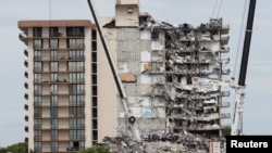 Petugas darurat melakukan upaya pencarian dan penyelamatan di lokasi bangunan tempat tinggal yang sebagian runtuh di Surfside, dekat Miami Beach, Florida, AS, 29 Juni 2021. (Foto: REUTERS/Joe Skipper)