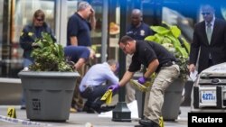 Un policía de Nueva York coloca marcas que establecen los casquillos del tiroteo frente al edificio Empire State, sobre la 5a. Avenida en Manhattan.