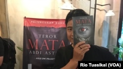 Agus Dwi Prasetyo, penulis buku ini, berpose dengan buku "Teror Mata Abdi Astina" karyanya. Tyo, sapaan akrabnya, adalah wartawan media nasional yang sehari-hari meliput di Gedung KPK, Jakarta, Minggu, 11 November 2018. (Rio Tuasikal/VOA)