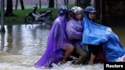 En la foto, personas en una moto pasando por una calle inundada tras el paso del tifón Damrey en la ciudad de Hue en Vietnam el 5 de noviembre de 2017