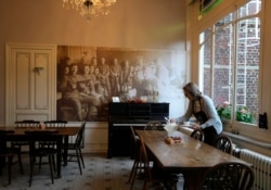 Volunteer Libby Madden, from Bath, England, sets a table in the breakfast room at Talbot House in Poperinge, Belgium, Ypres on Nov. 4, 2021.
