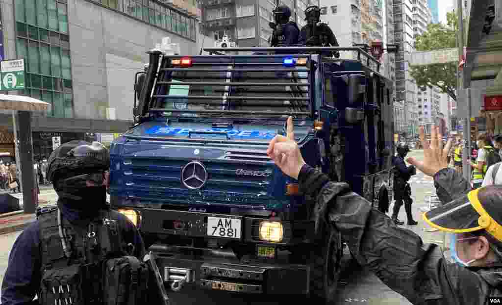 有市民在警方銳武裝甲車前高舉代表反送中運動”五大訴求、缺一不可”的”五一手勢”。(美國之音湯惠芸拍攝)