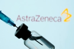 FILE PHOTO: A vial and sryinge are seen in front of a displayed AstraZeneca logo