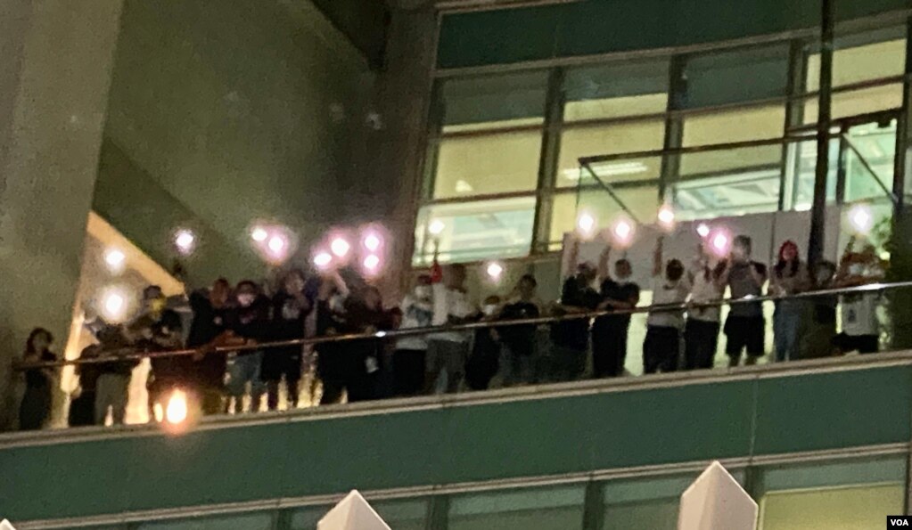 一批苹果日报编采人员6月24日凌晨在苹果日报大楼平台高举手机灯，向大楼外声援的市民表达谢意 (美国之音汤惠芸)(photo:VOA)