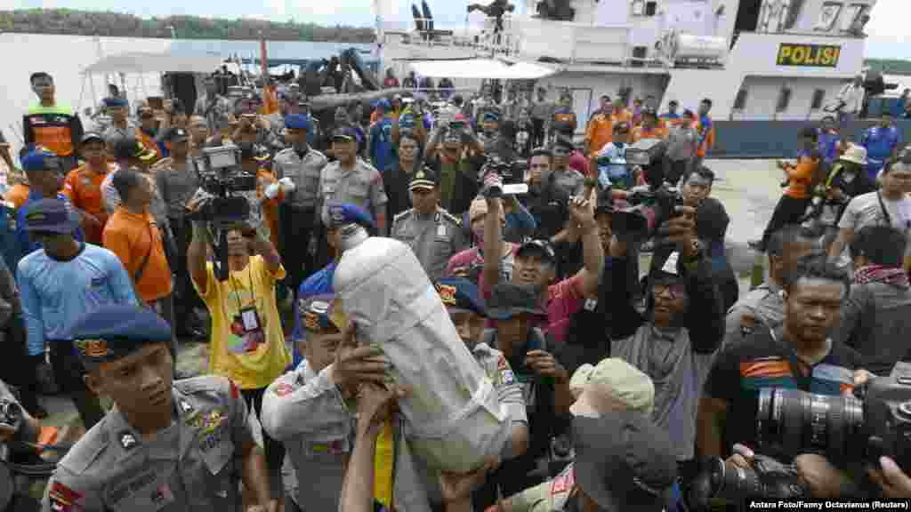 Police carry debris from a boat believed to be an oxygen tank from the AirAsia Flight 8501 jet at the Kumai Port, Pangkalan Bun, Central Kalimantan, Jan. 1, 2015.