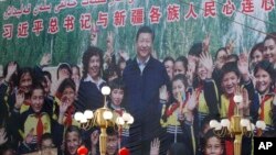 FILE - A propaganda poster showing Chinese President Xi Jinping with ethnic minority children and the slogan which reads "Party Secretary Xi Jinping and Xinjiang's multi ethnic residents united heart to heart" decorates the side of a building in Kashgar, western China's Xinjiang region, Aug. 31, 2018. 