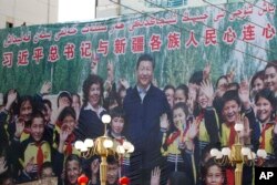 A propaganda poster showing Chinese President Xi Jinping with ethnic minority children and a slogan which reads "Party Secretary Xi Jinping and Xinjiang's multi-ethnic residents united heart to heart" are seen on the side of a building in Kashgar, in China's Xinjiang region, Aug. 31, 2018.