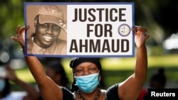 A protester holds a sign outside the Glynn County Courthouse during jury selection in Ahmaud Arbery's murder trial, in Brunswick, Georgia, Oct. 18, 2021.