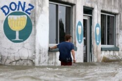 Logan Courvlle walks in front of a flooded business after Hurricane Barry in Mandeville, La., July 13, 2019.