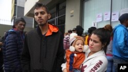 La pareja de migrantes venezolanos Johan Alvarez y Daniela Tovar, con su hijo Matías, hablan durante una entrevista afuera de una oficina de refugiados dirigida por la Secretaría Ejecutiva de la Comisión Especial para Refugiados de Perú.