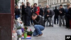 Một cư dân Paris khóc khi đặt hoa phía trước quán cà phê Carillon tại Paris, ngày 14/11/2015. 