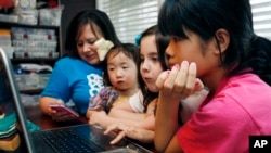 Perempuan keluarga Smith, dari kiri ke kanan, ibu Niki Smith, GiGi, 3, Macy Jade, 7 dan Guan Ya, 14, menggunakan Google Translate untuk berkomunikasi di rumah mereka di Mississippi. (AP/Rogelio V. Solis)