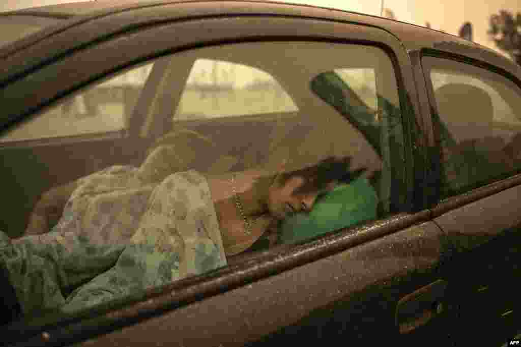 People sleep in their car on the beach as a wildfire burns in Pefki village on Evia (Euboea) island, the second largest Greek island, Aug. 8, 2021.