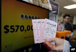 ARCHIVO-Un cliente muestra sus tickets de la lotería Powerball en una tienda de Chicago, el sábado 6 de enero de 2018,