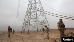 Soldiers loyal to Yemen's government search for landmines left by the Houthi rebels next to destroyed transmission towers in the Mas area, of Marib, Dec. 26, 2015.