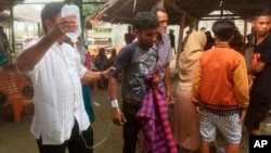 An ethnic-Rohingya man, center, is assisted by a paramedic after a group of Rohingya Muslims was brought ashore in Bireuen, Aceh province, Indonesia, April 20, 2018.