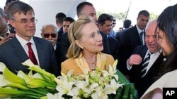 US Secretary of State Hillary Clinton is presented flowers as she tours the Red Crescent with US Ambassador to Tunisia Gordon Grey, left, in Tunis, March, 17, 2011