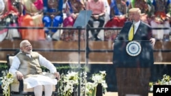 PM India Narendra Modi yang tersenyum saat Presiden AS Donald Trump (kanan) menyampaikan sambutan di Stadion Sardar Patel di Motera, luar Ahmedabad, India, 24 Februari 2020.