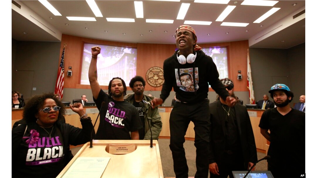 Stevante Clark stands on a desk as he shouts the name of his brother Stephon Clark, who was fatally shot by police a week earlier, during a meeting of the Sacramento City Council in Sacramento, California, March 27, 2018.