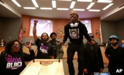 Stevante Clark stands on a desk as he shouts the name of his brother Stephon Clark, who was fatally shot by police a week earlier, during a meeting of the Sacramento City Council in Sacramento, California, March 27, 2018.
