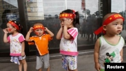 资料照片：北京奥运会开幕式当天，头戴“中国加油”标语的幼儿在天安门广场附近。(2008年8月8日)