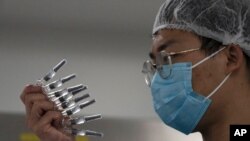 지난 24일 중국 베이징 시노백 공장에서 생산한 신종 코로나바이러스 백신을 직원이 육안 검사하고 있다.