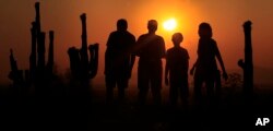 FILE - People view an annular solar eclipse as they look towards the setting sun on the horizon in Phoenix, Arizona, May 20, 2012.