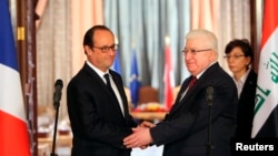 French President Francois Hollande shakes hands with Iraqi President Fuad Masum, right, during a news conference in Baghdad, Sept. 12, 2014. 