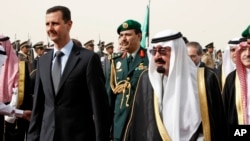 FILE - King Abdullah of Saudi Arabia, right, welcomes Syrian President Bashar Assad upon his arrival to attend the Arab Summit, in the Saudi capital Riyadh, March 11, 2009.